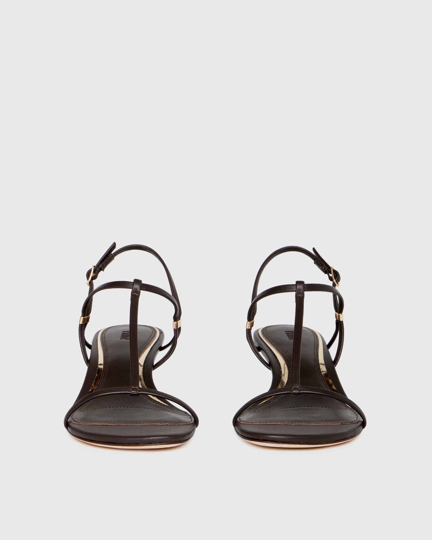 Chocolate wedge sandal with thin straps on a light gray background