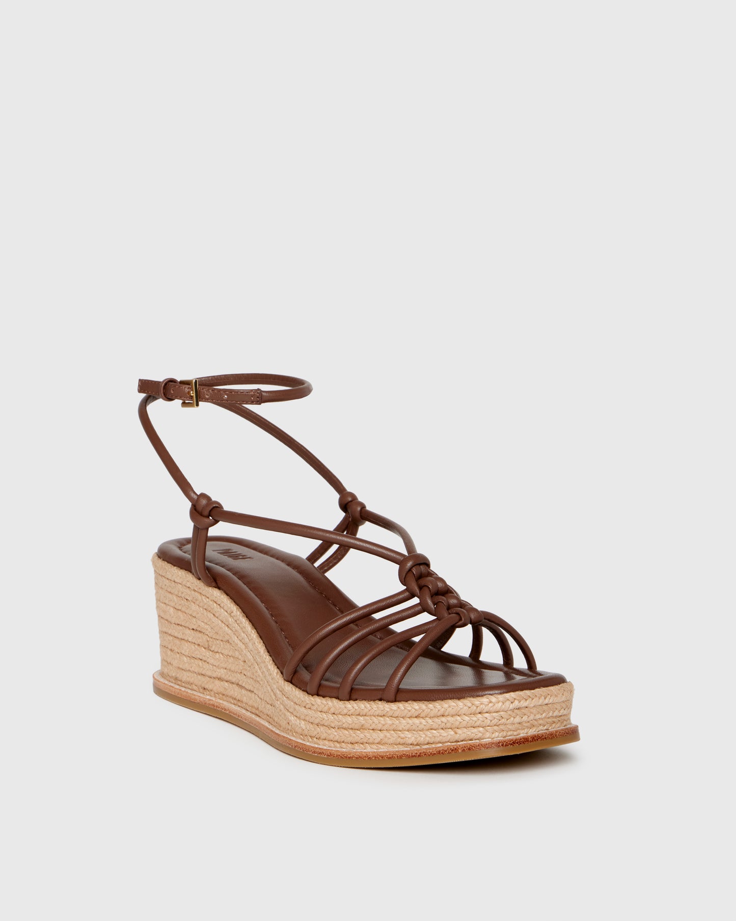 Brown wedge sandal with espadrille sole on a light gray background