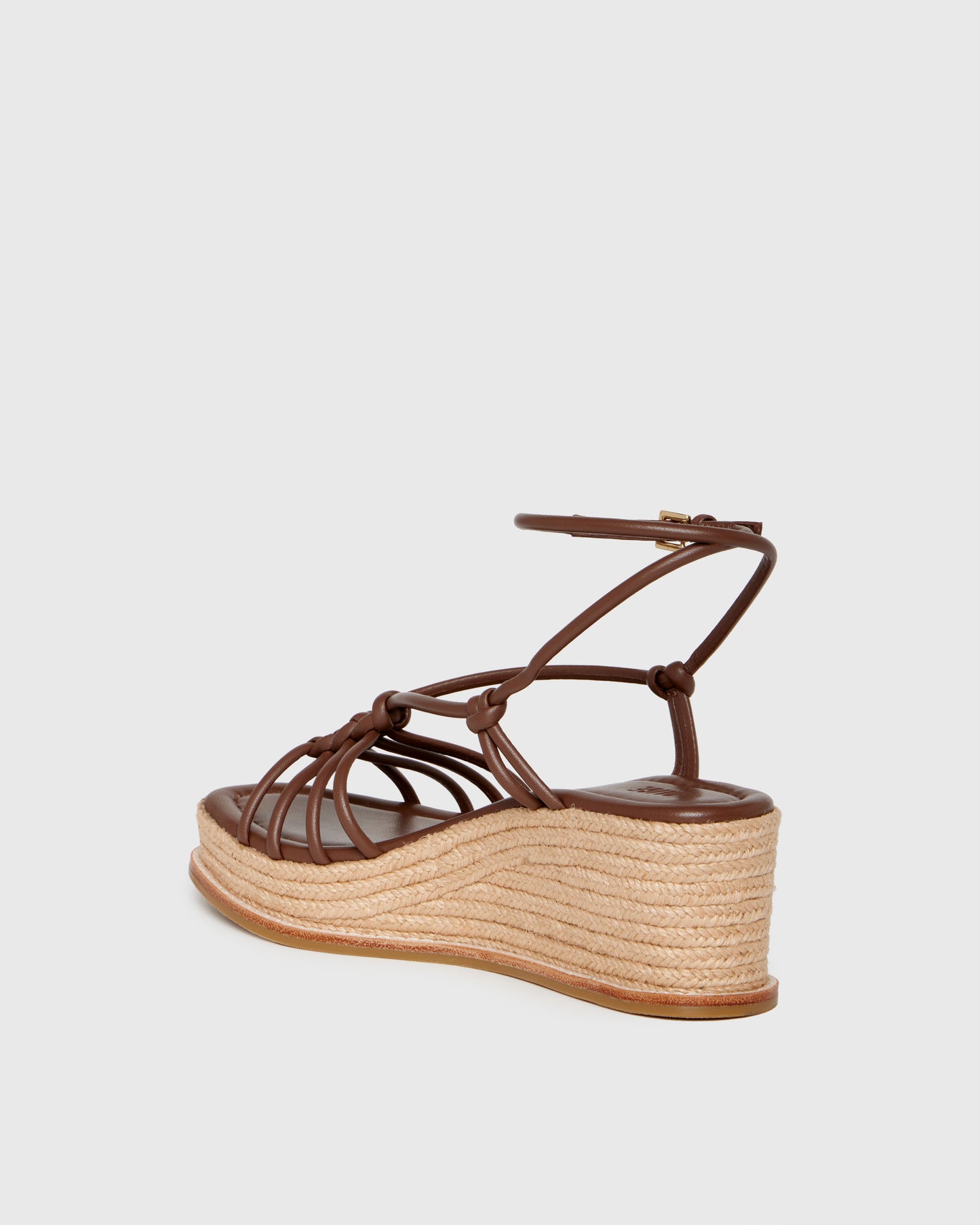 Brown wedge sandal with espadrille sole on a light gray background