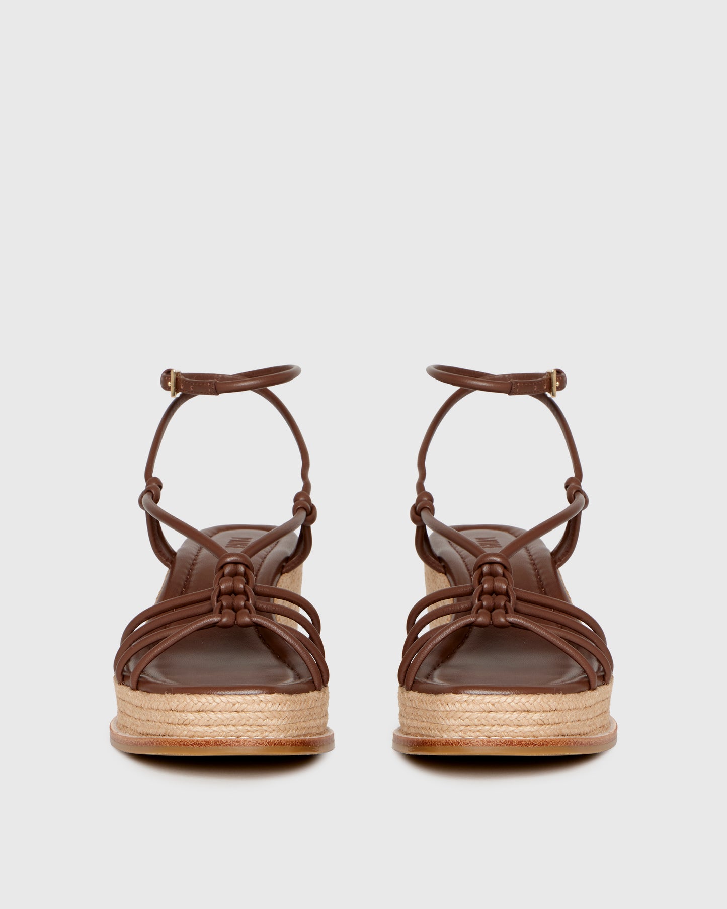 Brown wedge sandal with espadrille sole on a light gray background