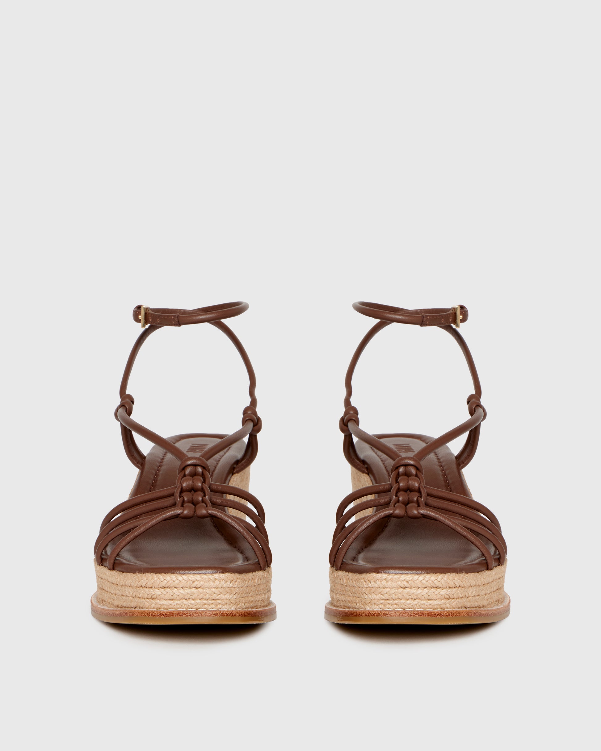 Brown wedge sandal with espadrille sole on a light gray background