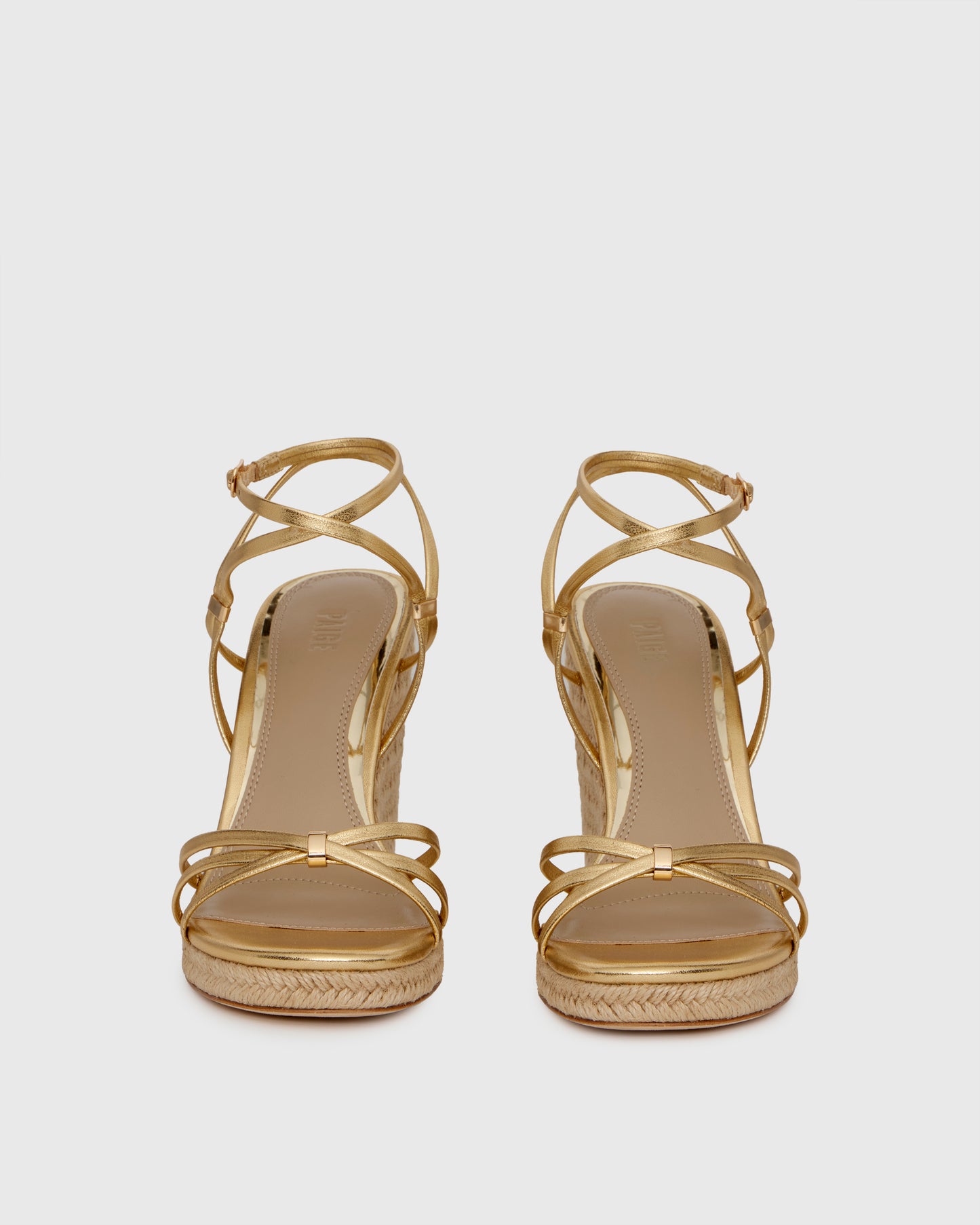 Gold wedge sandal with espadrille sole on a light gray background