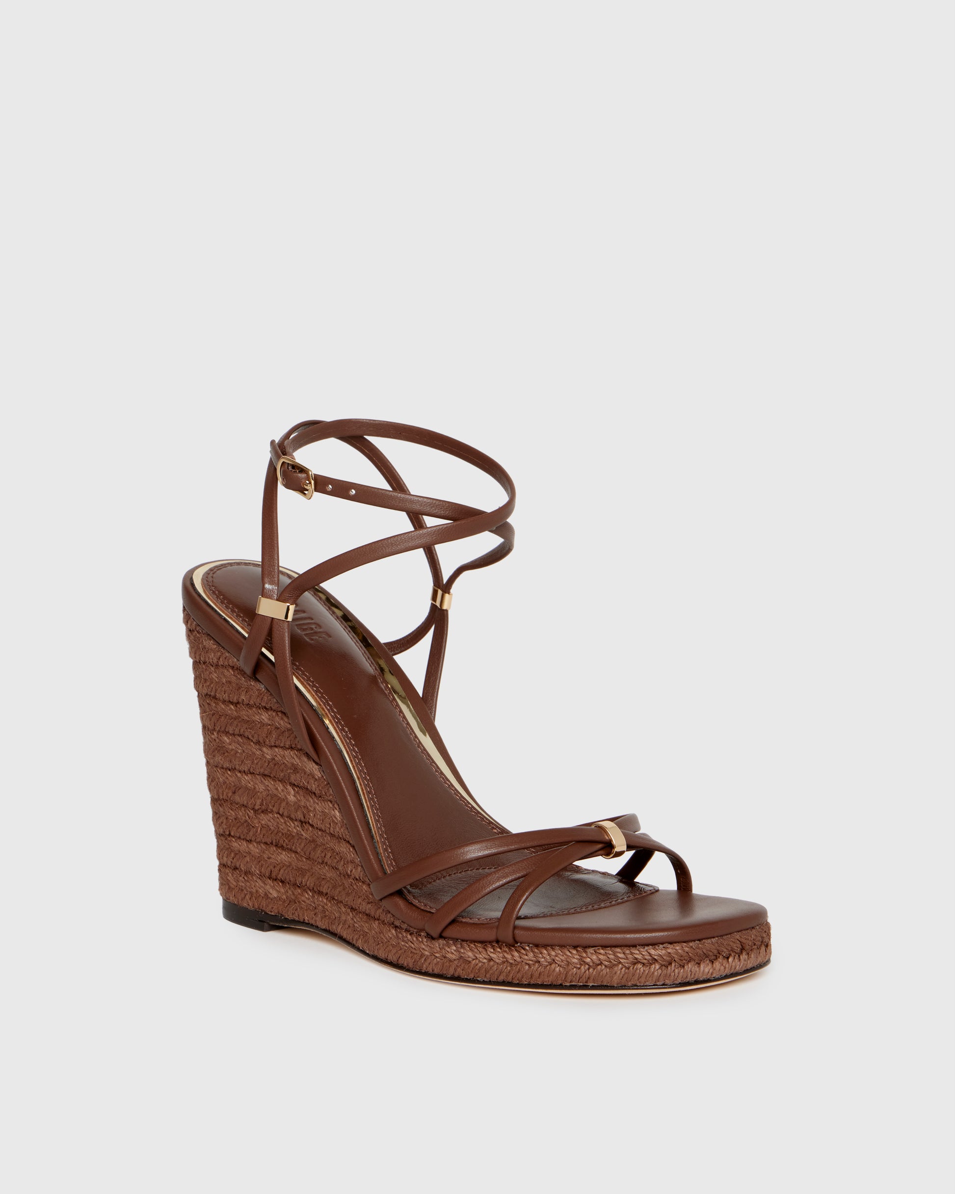 Brown wedge sandal with espadrille sole on a light gray background