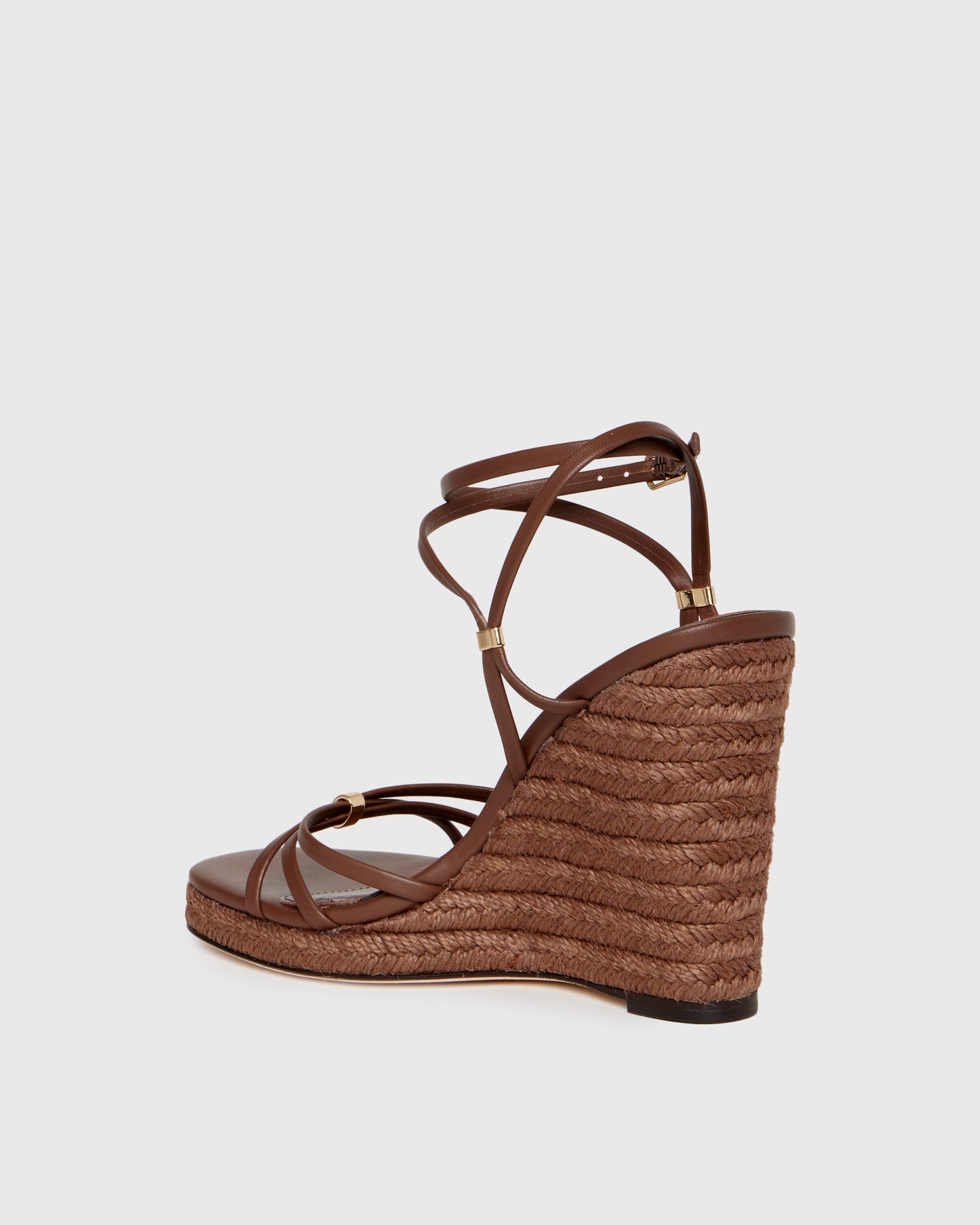 Brown wedge sandal with espadrille sole on a light gray background