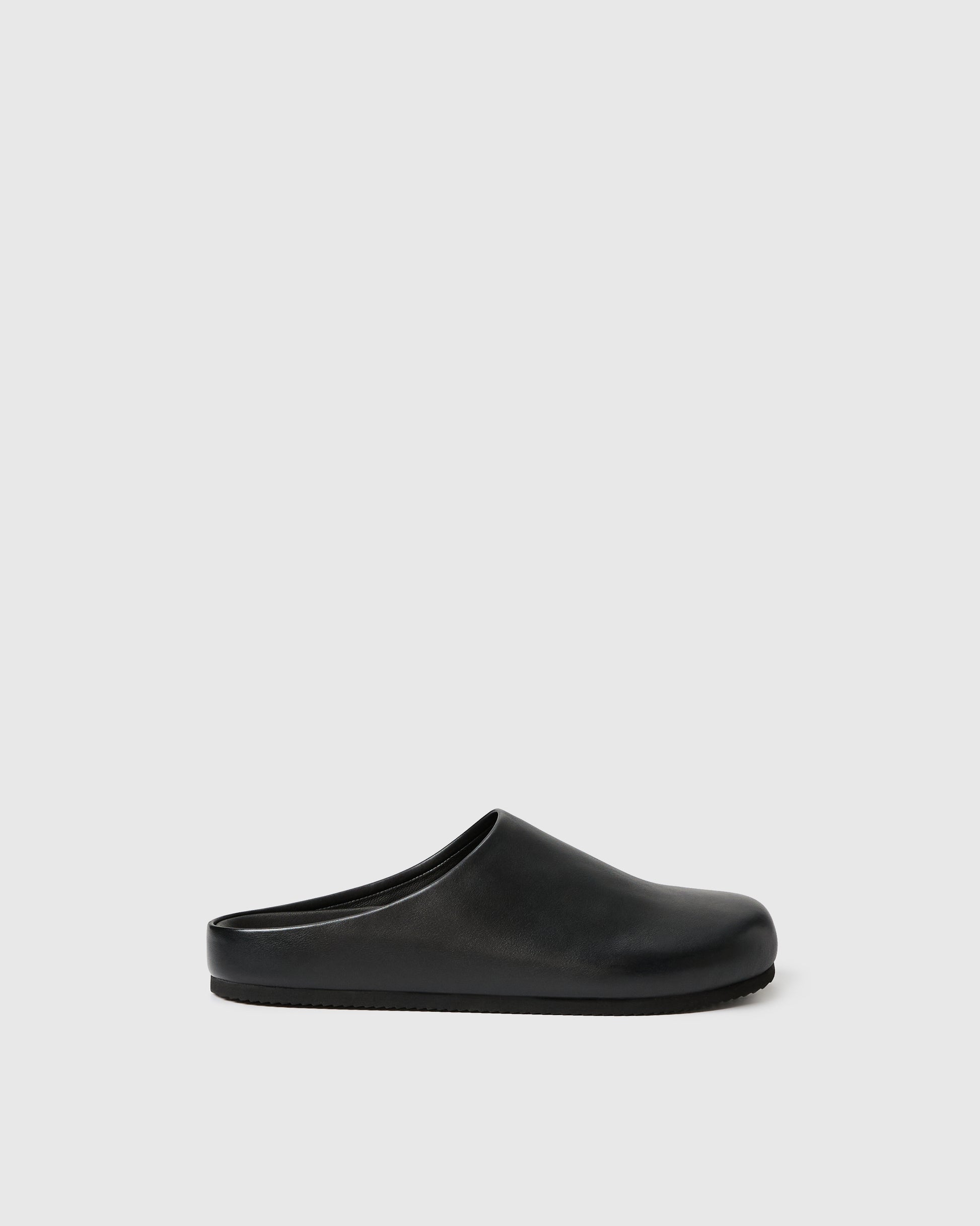 Black slip-on clog-style shoe with a smooth upper set against a white background.