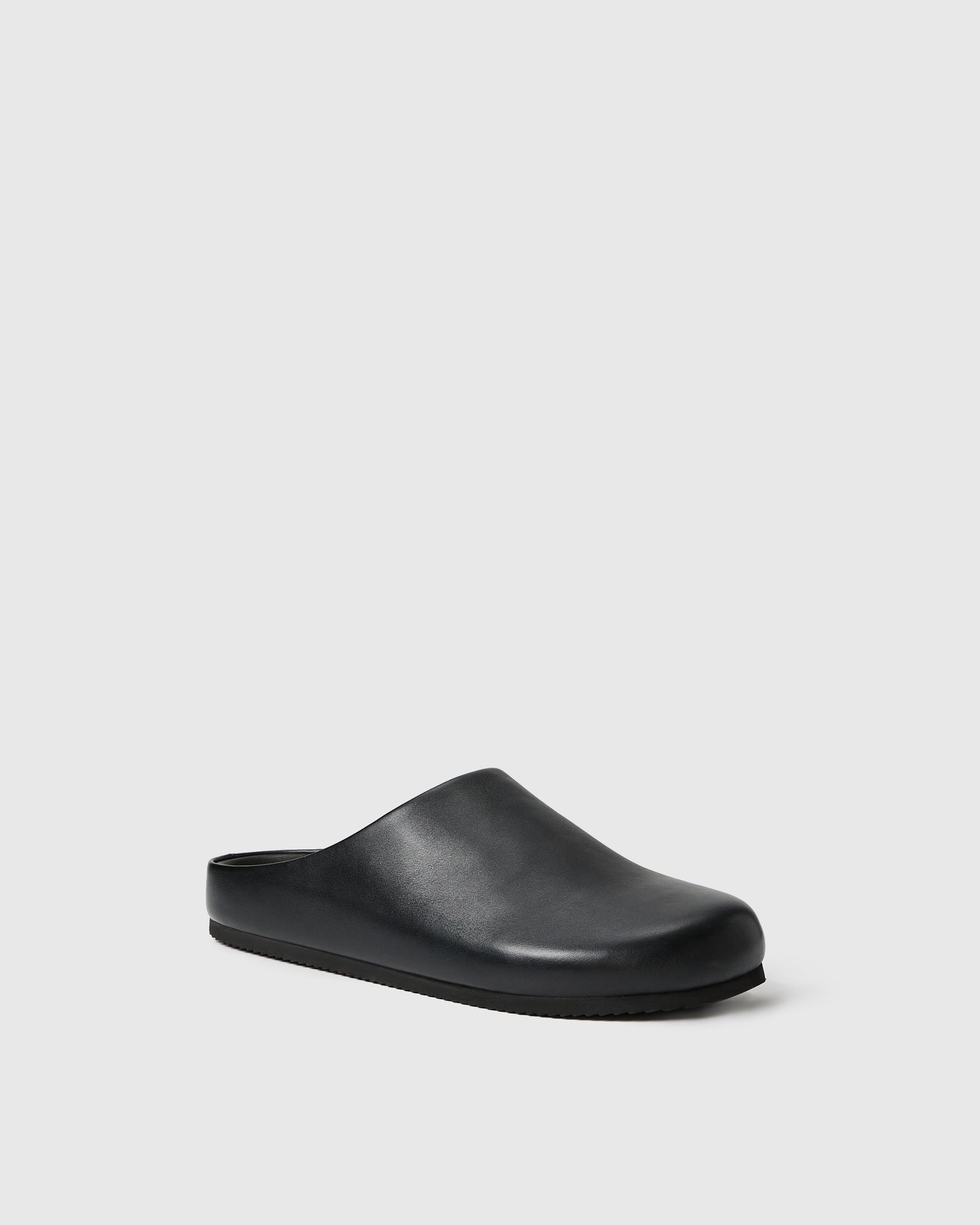Black slip-on clog-style shoe with a smooth upper set against a white background.