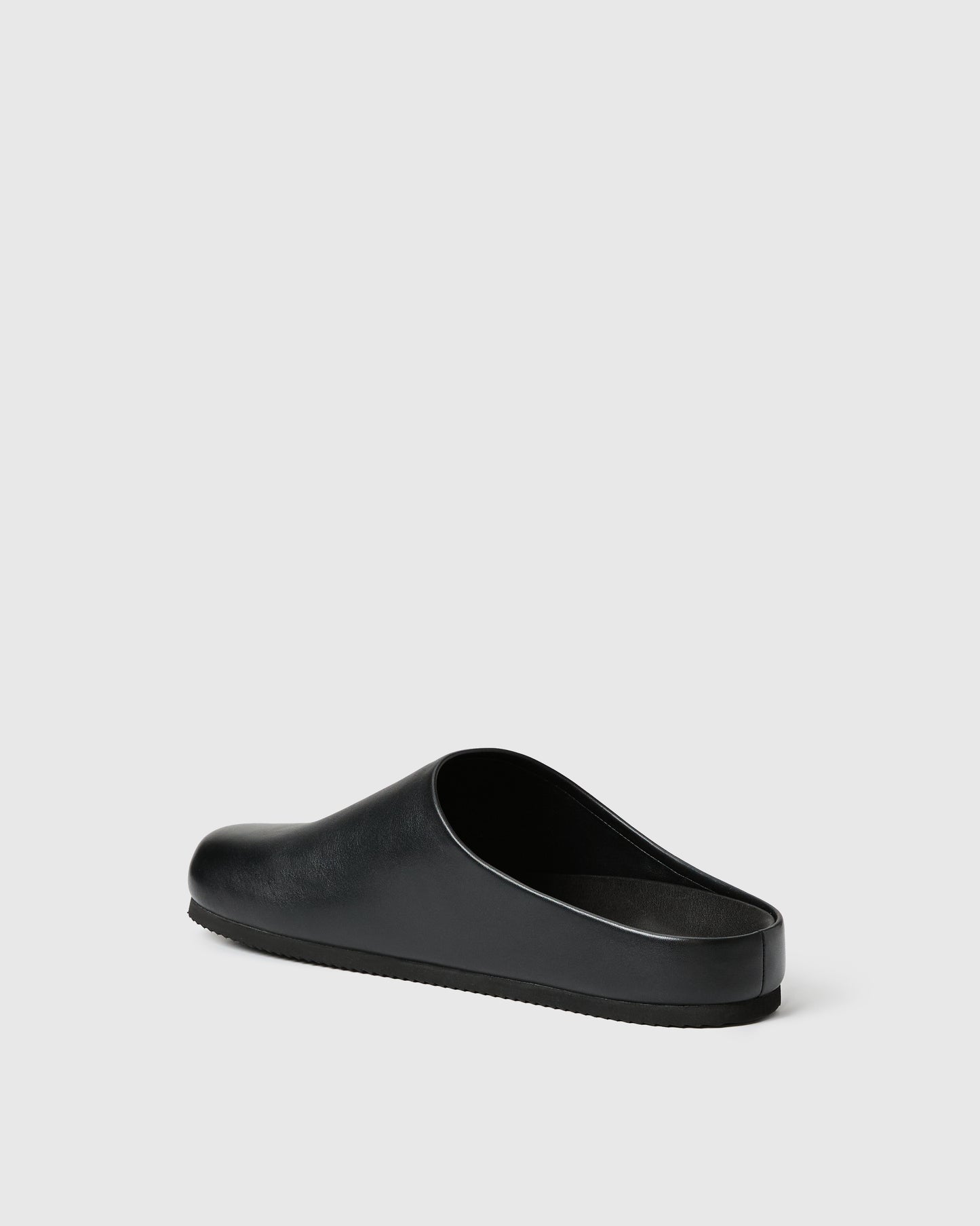 Black slip-on clog-style shoe with a smooth upper set against a white background.