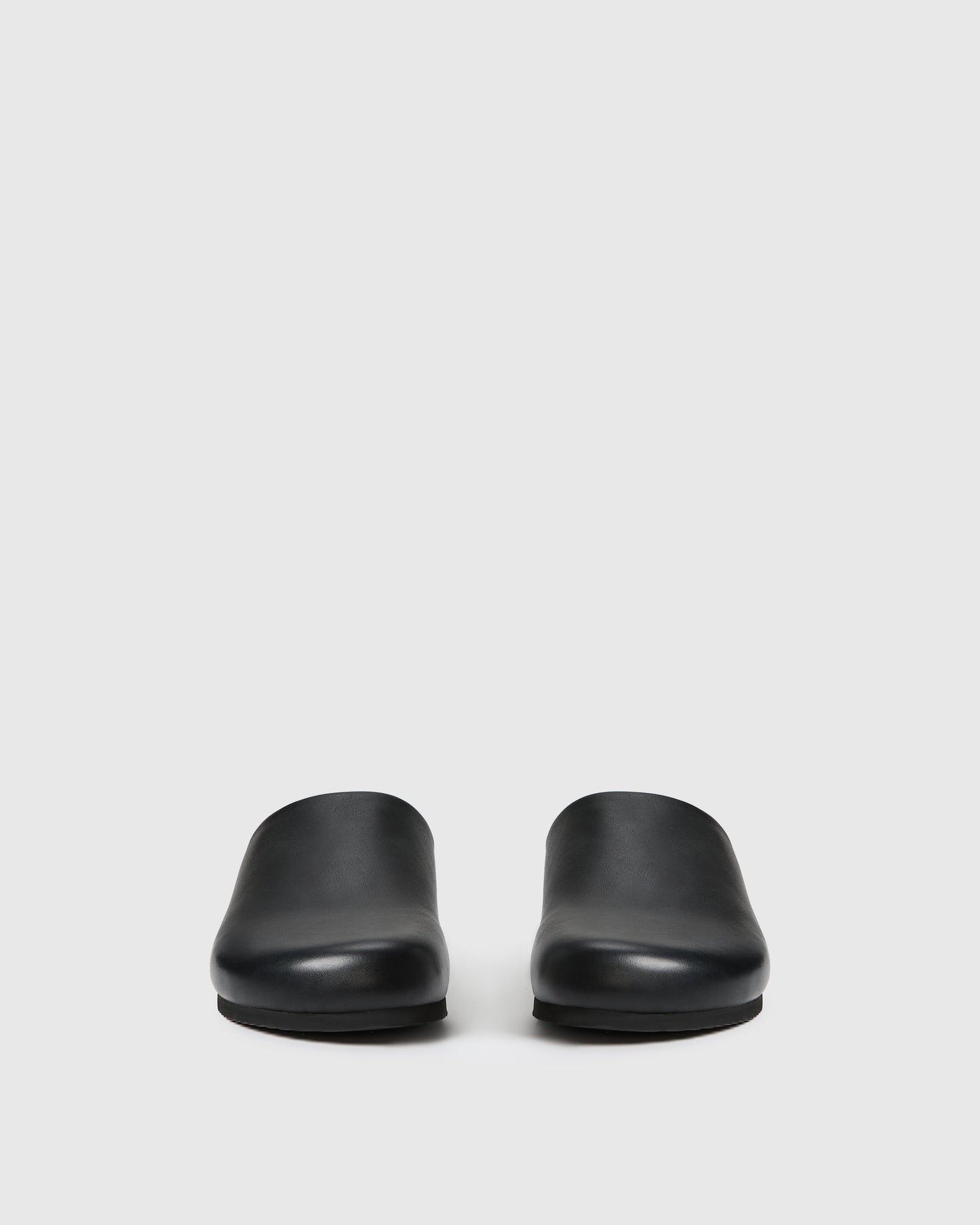 Black slip-on clog-style shoe with a smooth upper set against a white background.