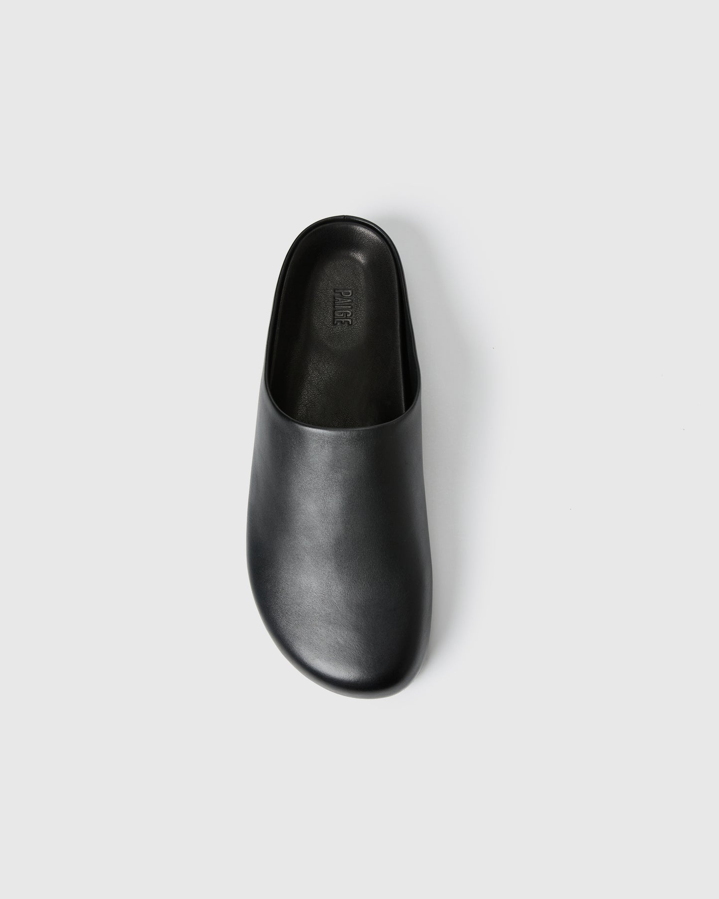 Black slip-on clog-style shoe with a smooth upper set against a white background.