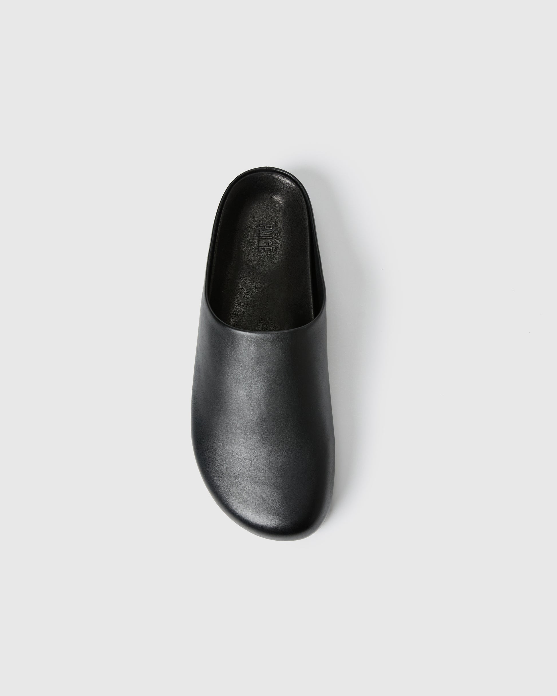 Black slip-on clog-style shoe with a smooth upper set against a white background.