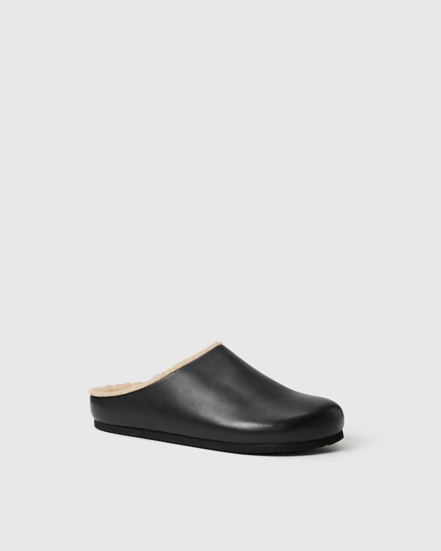 Black slip-on clog-style shoe with a smooth upper and plush shearling lining, set against a white background.