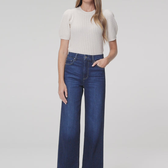 Women wearing white shirt, blue jeans paired with black flat against a white background