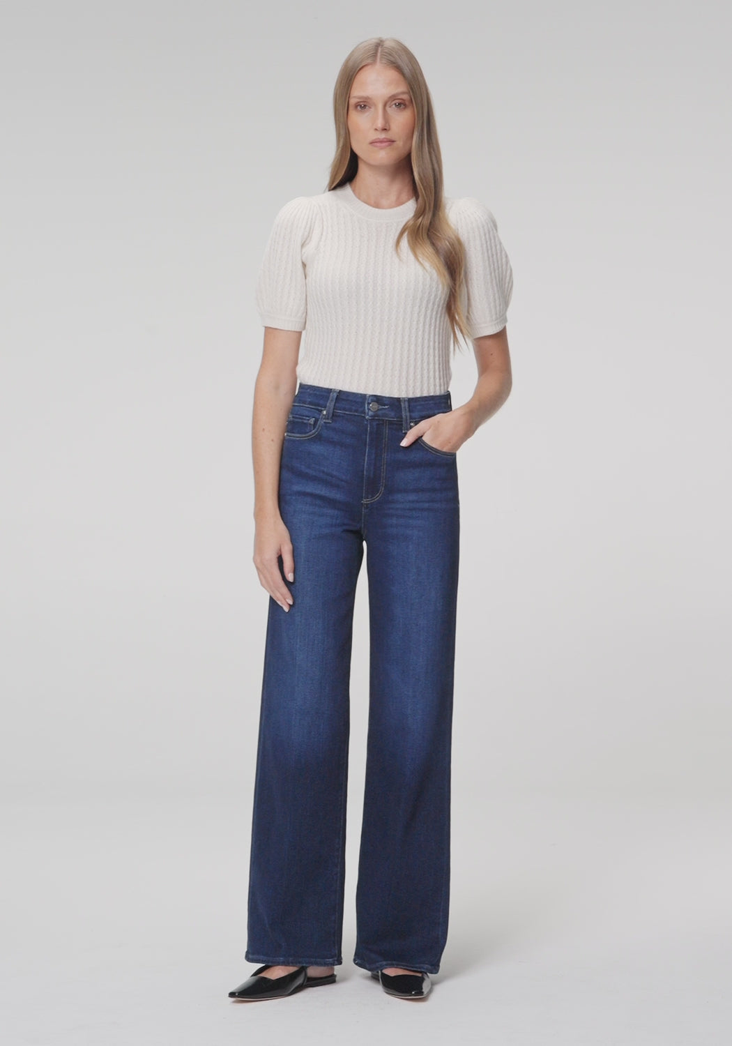 Women wearing white shirt, blue jeans paired with black flat against a white background