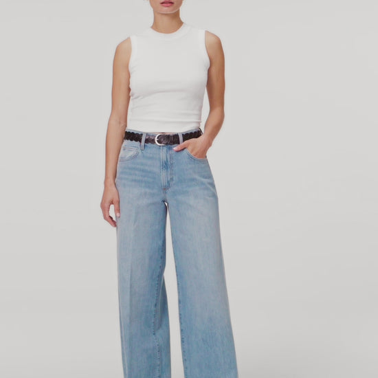 women wearing white top paired with blue jeans against white background